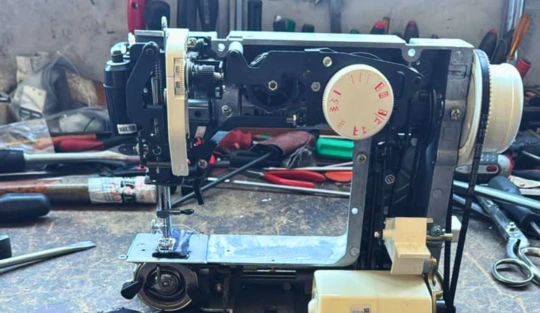 Meccanica interna di una macchina da cucire aperta su un banco da lavoro